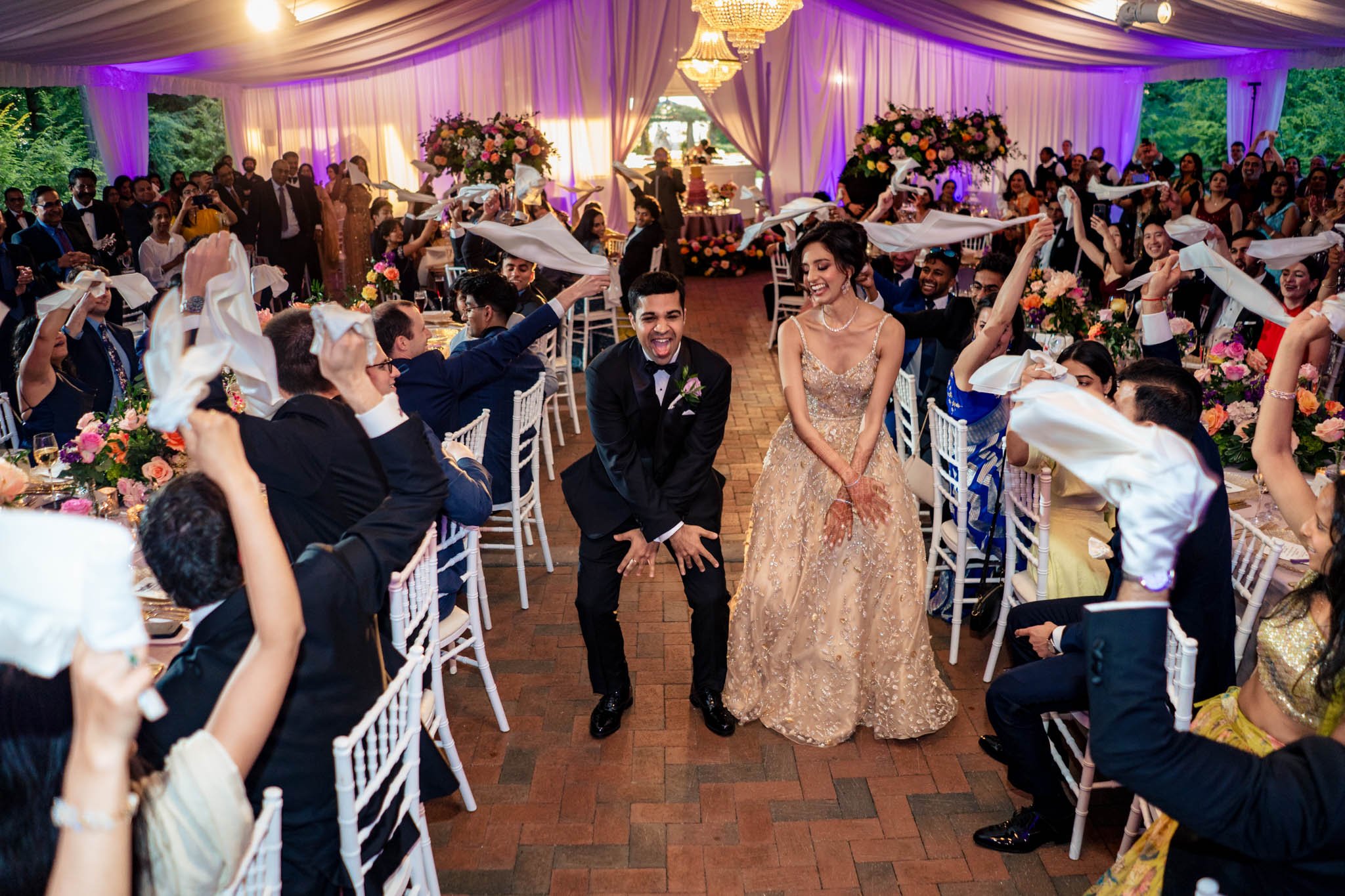 A bride and groom waving their hands in the air at a Biltmore Estate wedding reception.
