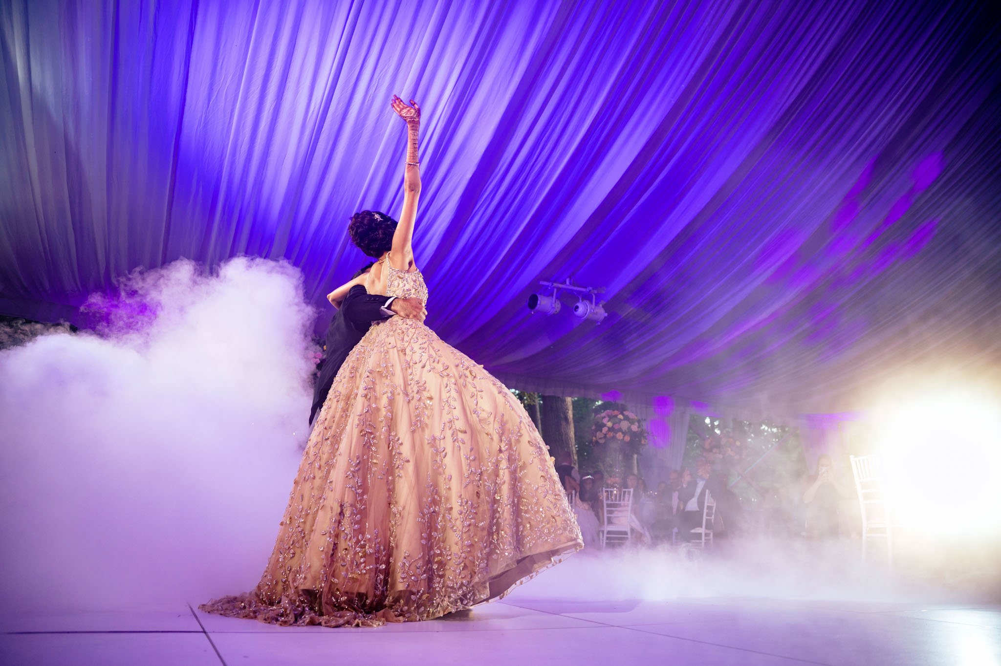 A woman in a gold dress is dancing on a stage at a Biltmore Estate wedding.