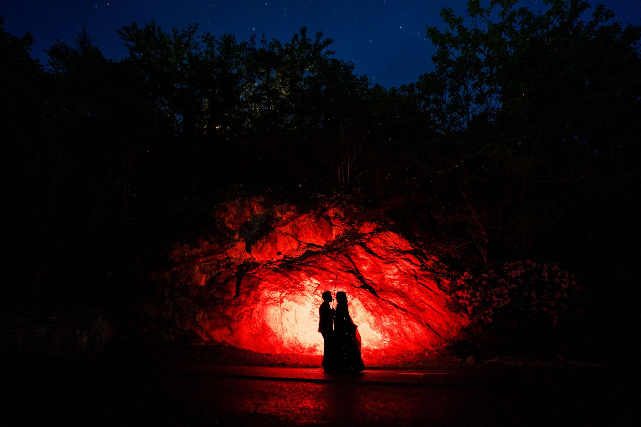 A couple standing in front of a red cave at night during a Biltmore Estate wedding.