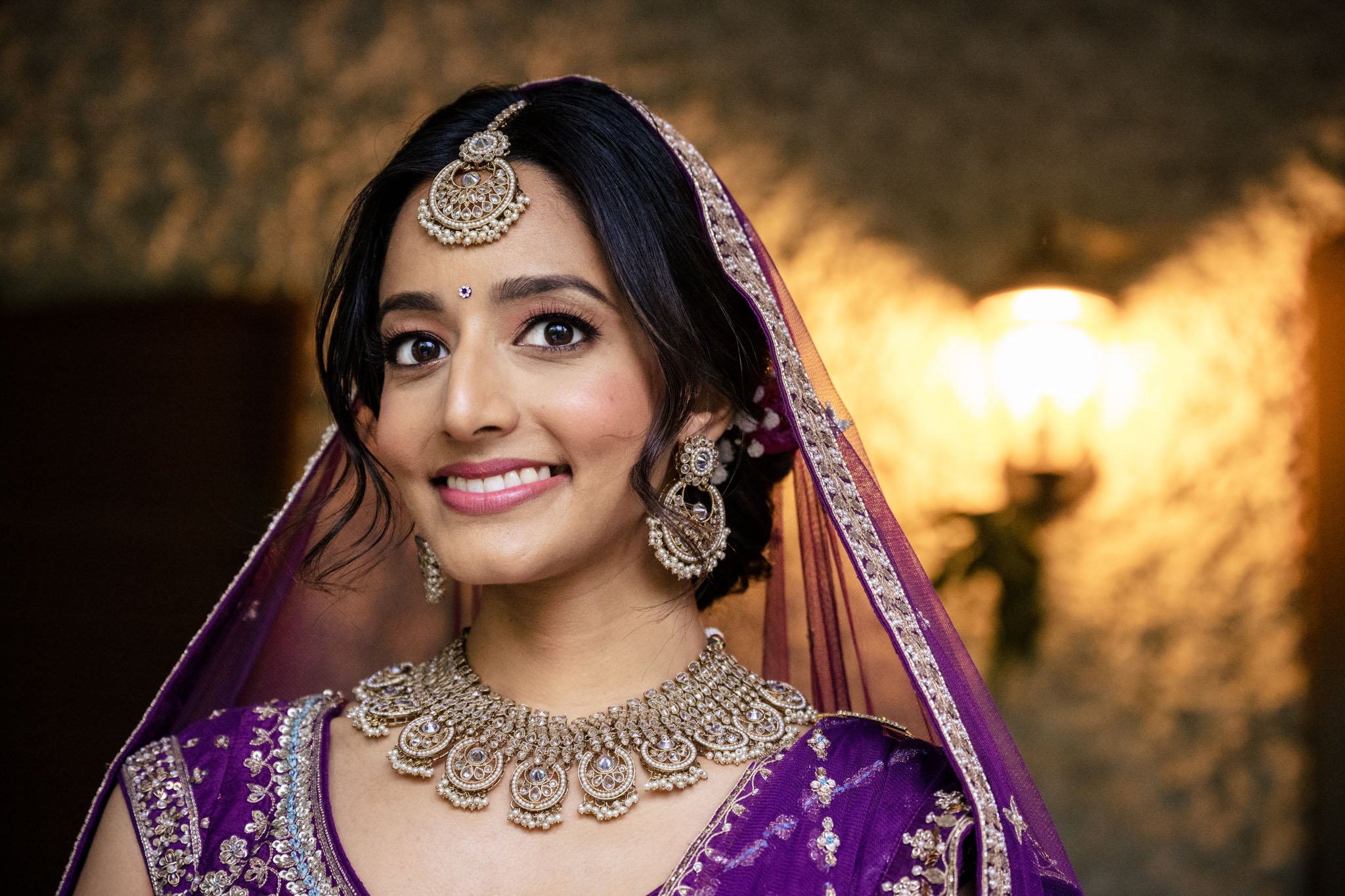 An Indian bride in a purple lehenga posing for a photo at a Biltmore Estate wedding.