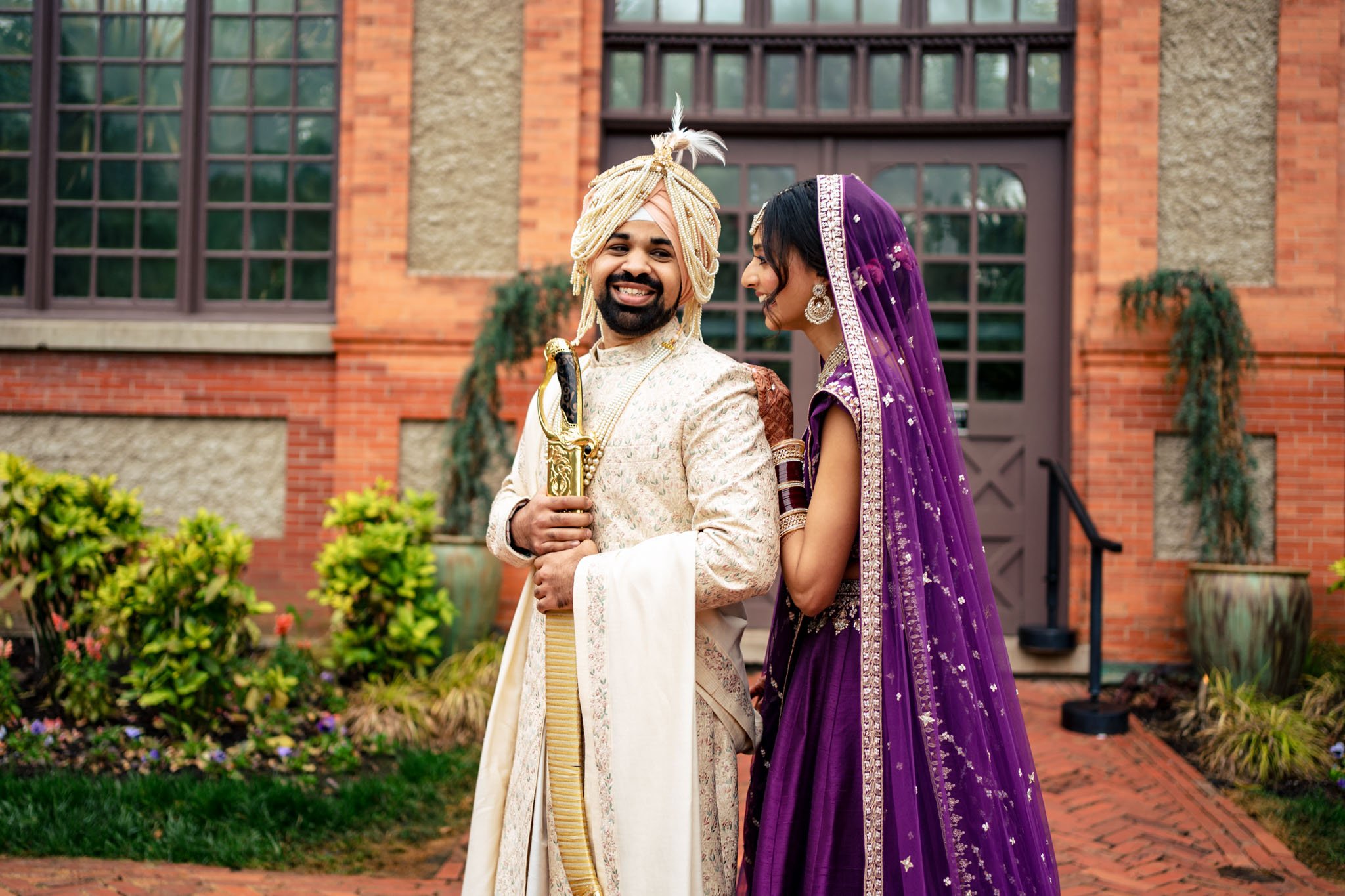 An Indian bride and groom standing in front of the Biltmore Estate building on their wedding day.