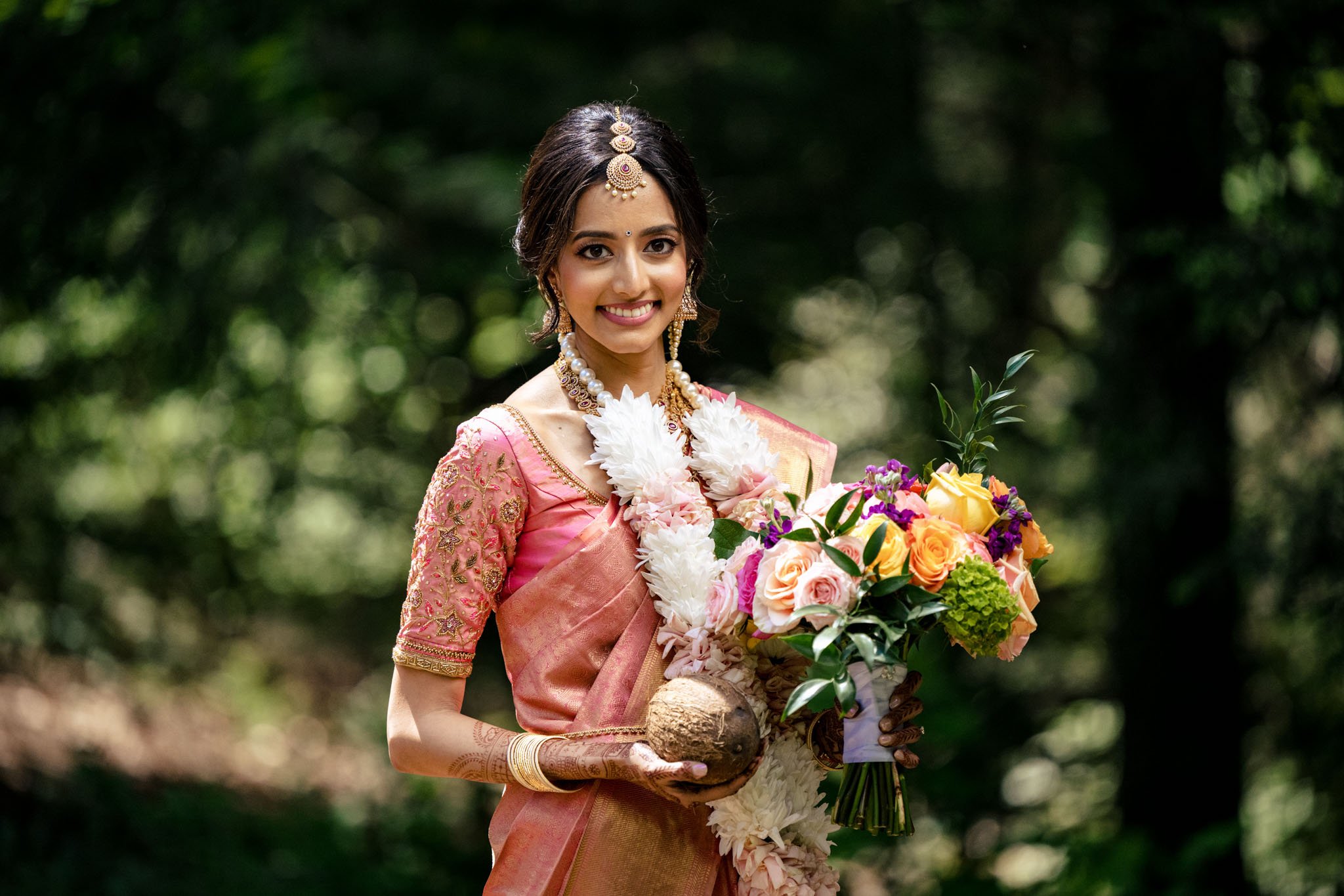 An Indian bride at the Biltmore Estate wedding in a pink sari holding a bouquet.