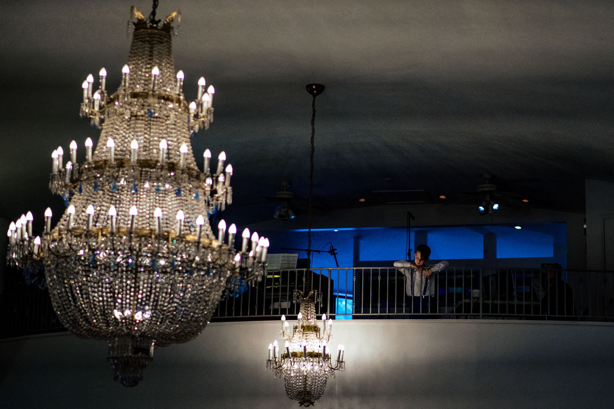 A wedding photographer captures a man standing in a room with a chandelier.