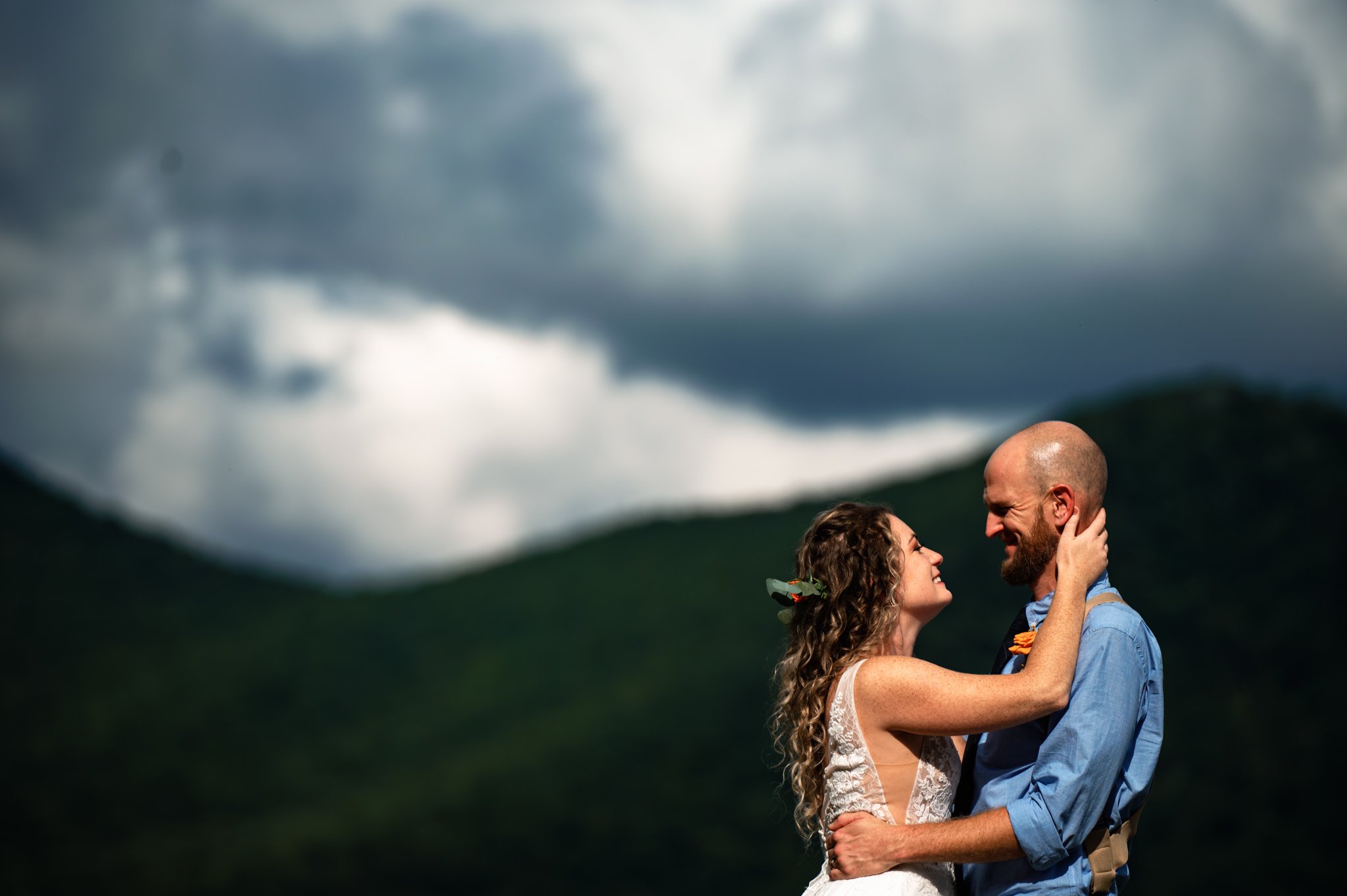 A bride and groom embracing in front of a mountain at their Asheville wedding.
