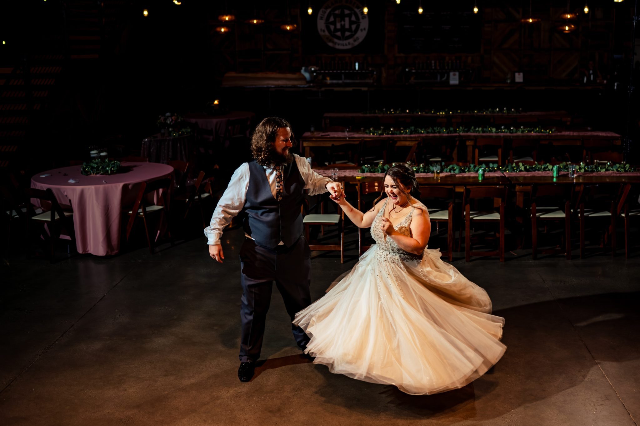 A bride and groom dancing at a highland brewing wedding in a barn.