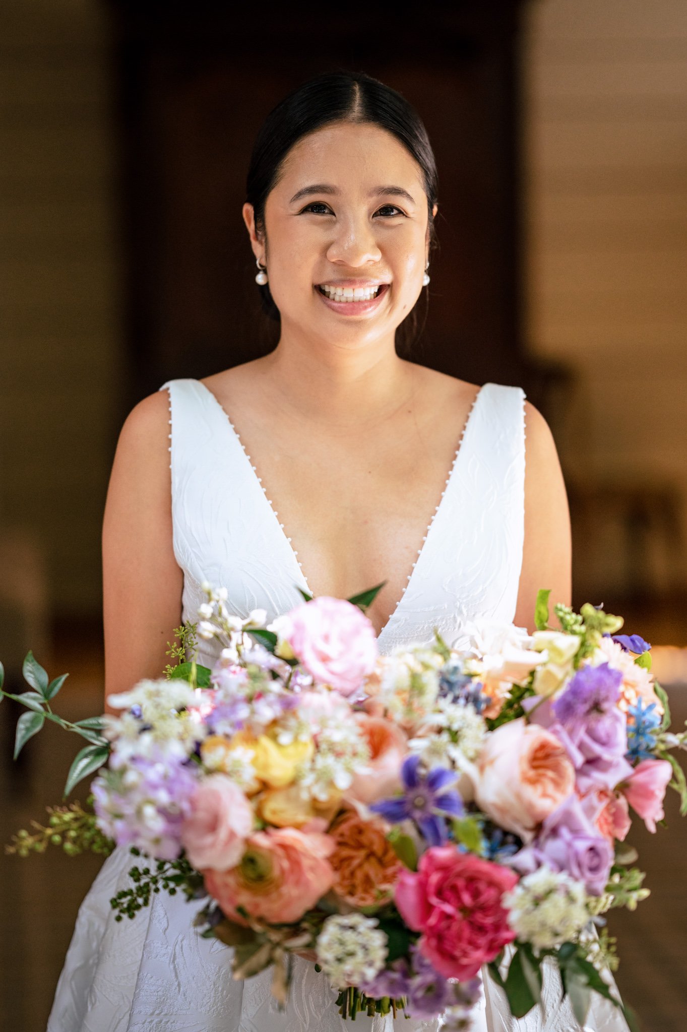 A bride in a white dress holding a colorful bouquet.