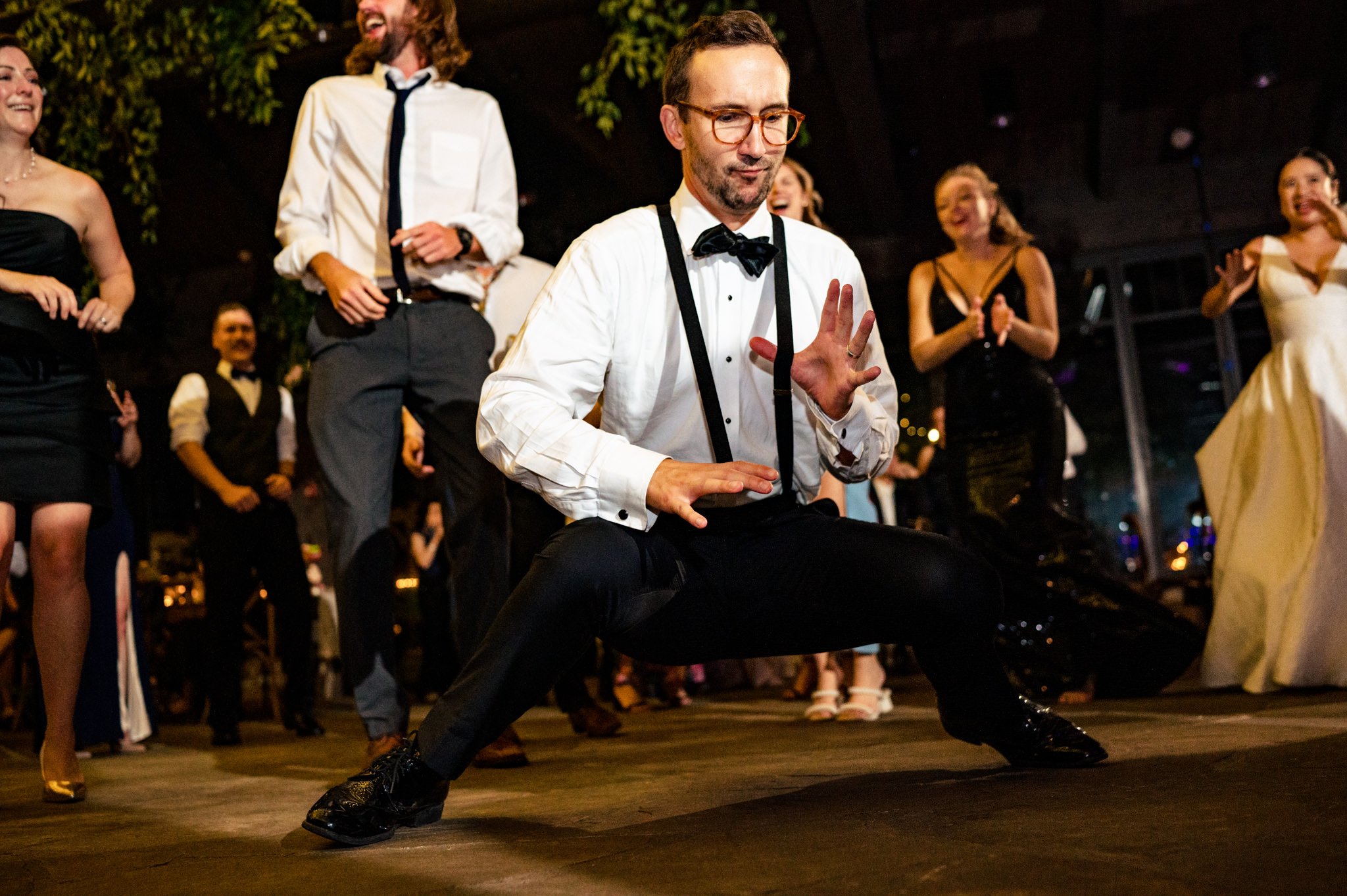 A man in a tuxedo dancing at a farm wedding.
