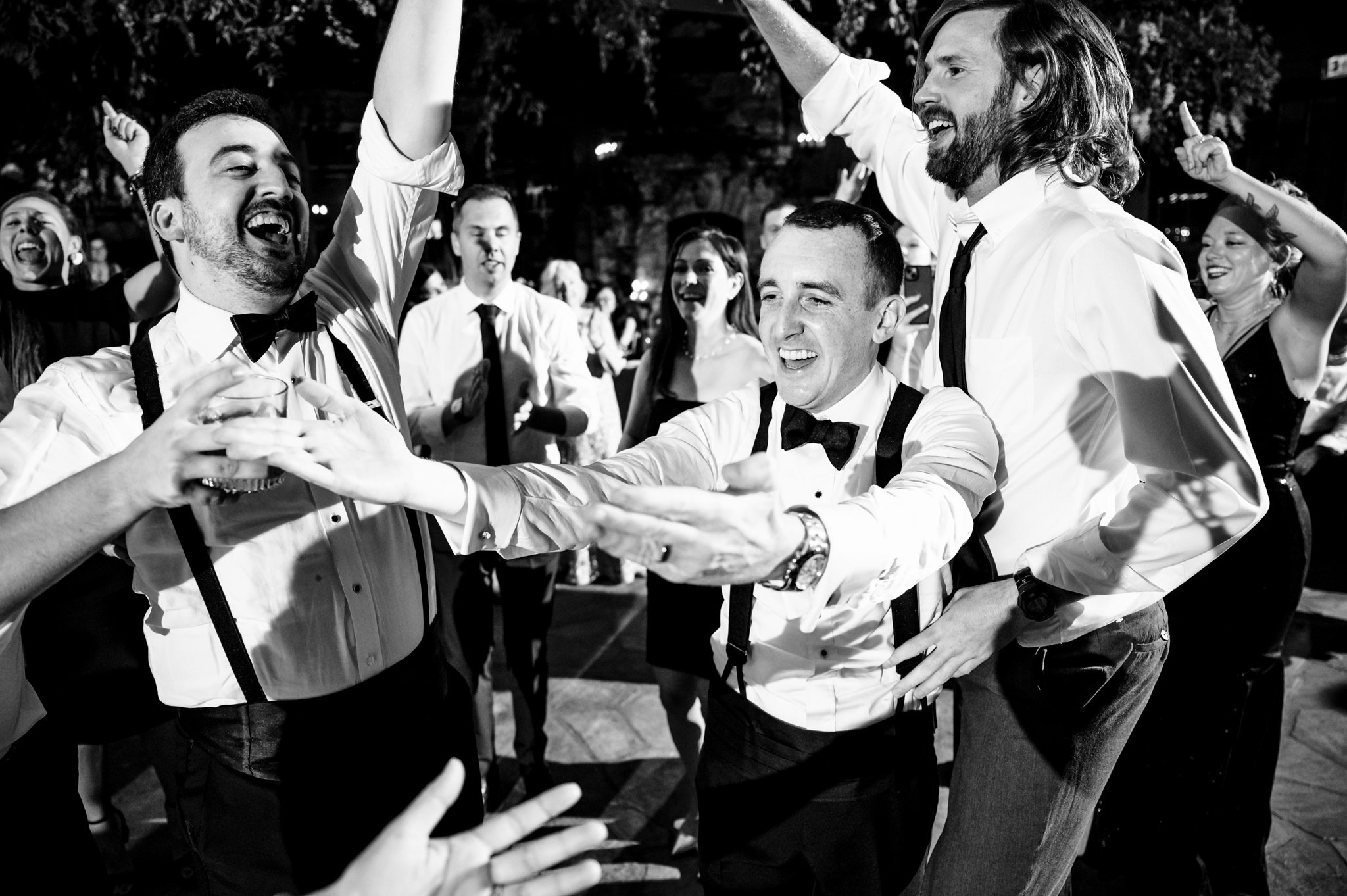 A black and white photo of men dancing at a wedding.