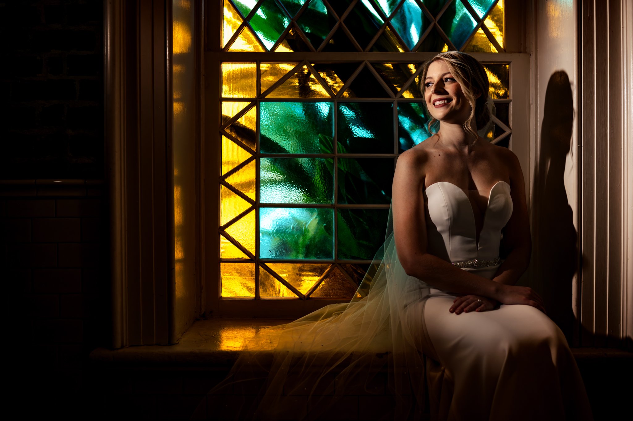 A bride sits in front of a stained glass window at Felicity Church in New Orleans for her wedding.