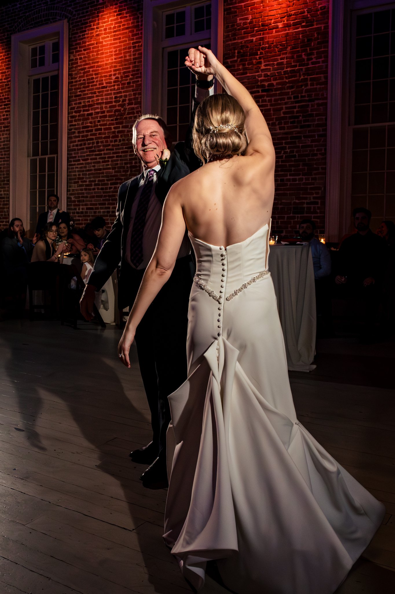 A bride and groom happily dance in front of a brick wall during their Felicity Church wedding in New Orleans.