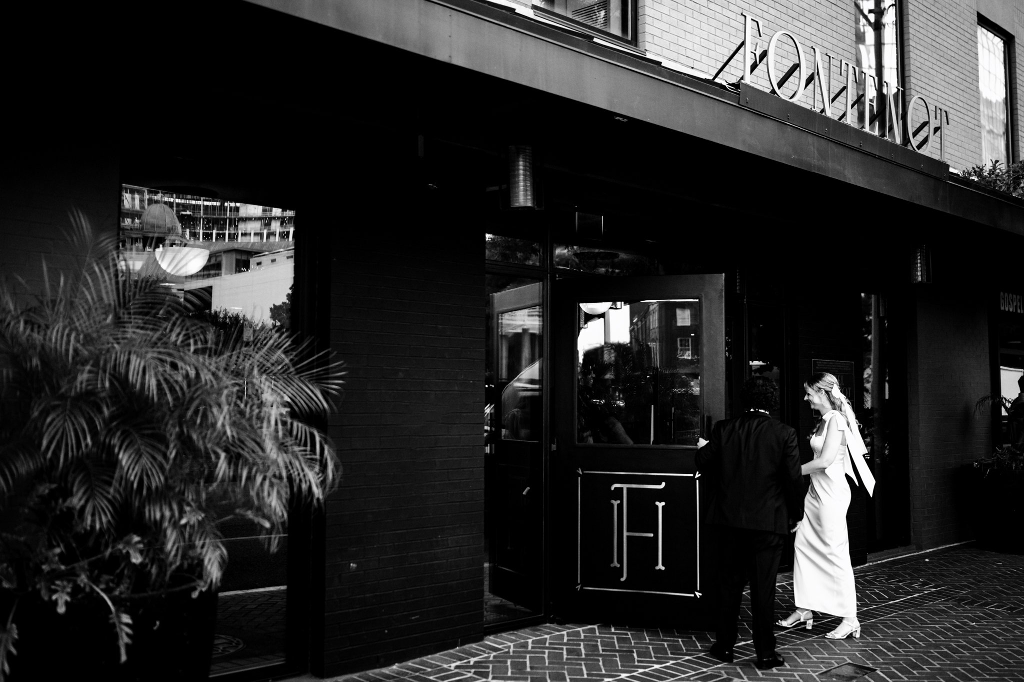 A new orleans bride and groom standing outside of a restaurant.