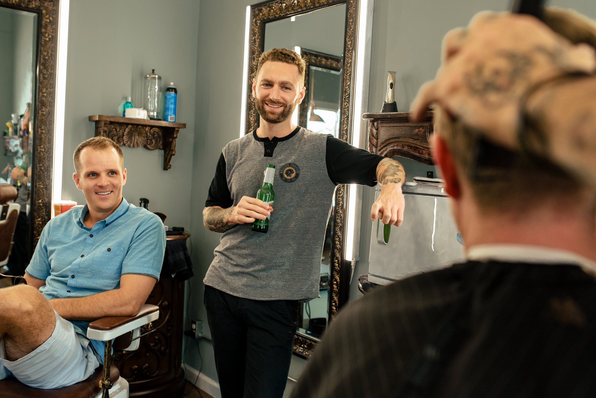 The best man sitting in a barber chair with a beer in his hand.