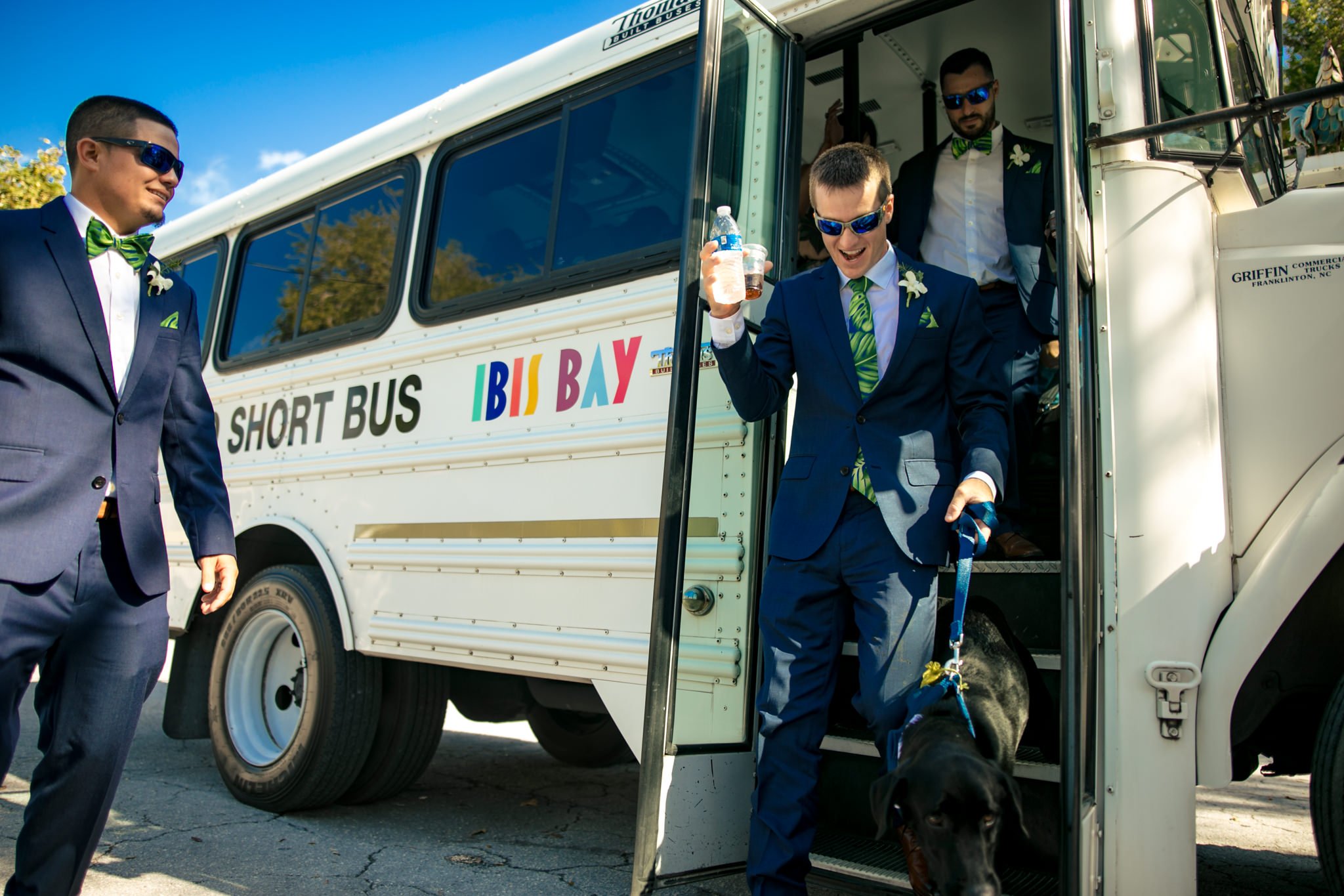 The best man and a groomsman, accompanied by a dog, boarding a bus.