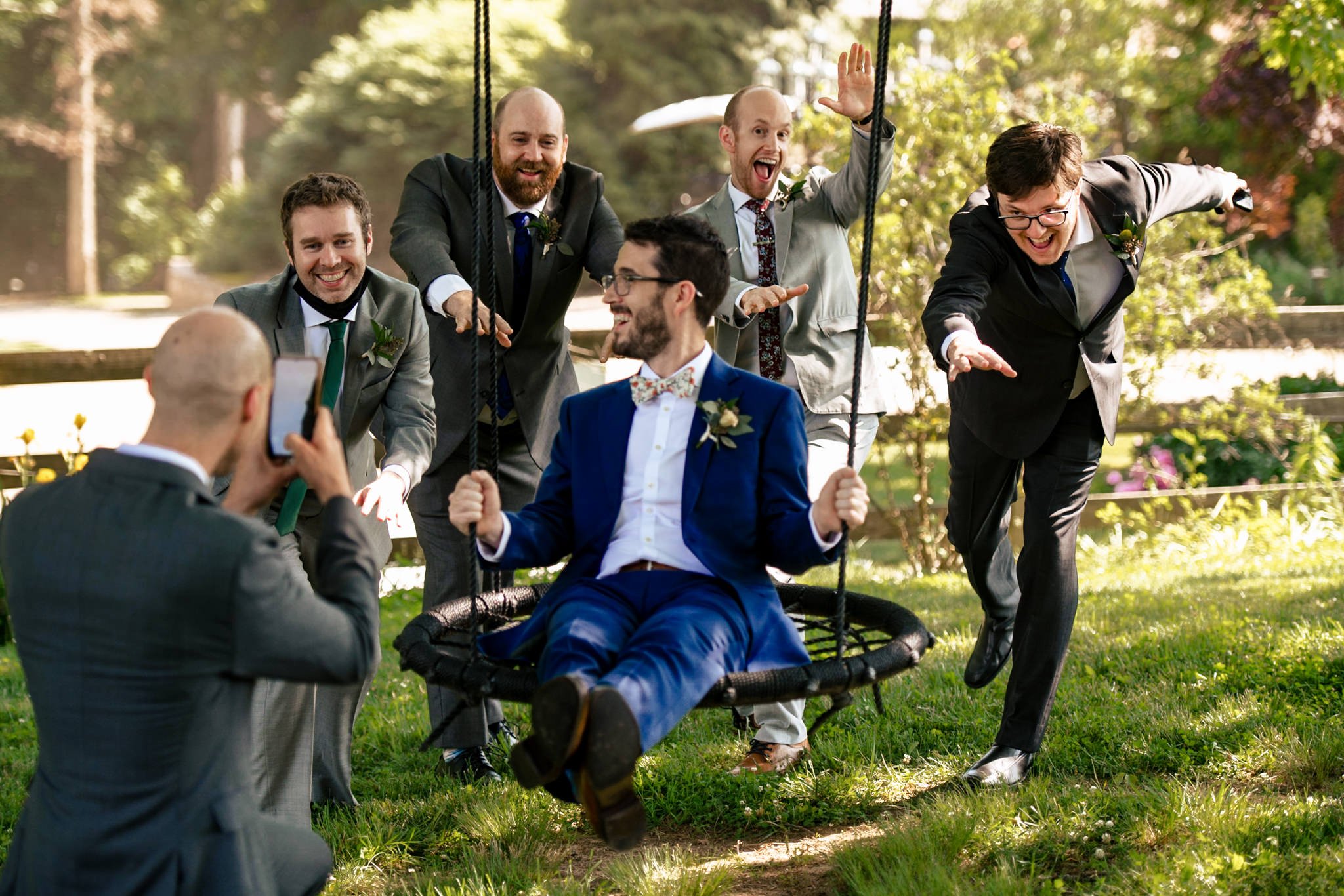 A group of groomsmen, including the best man, on a swing.