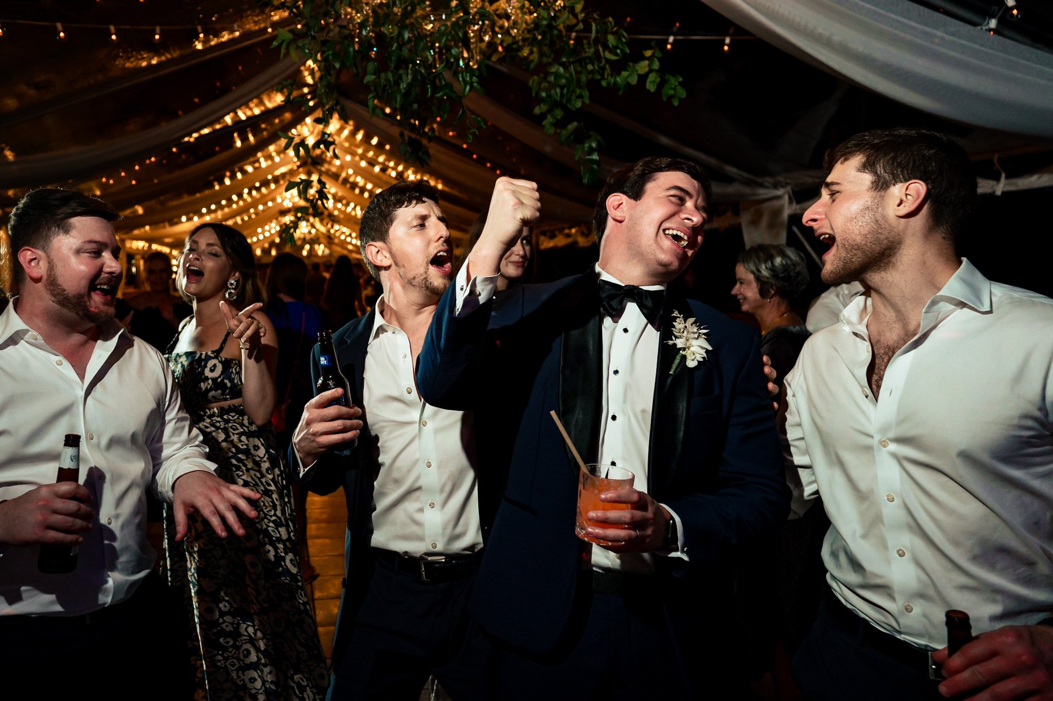 The best man and his group of men in tuxedos celebrating at a wedding.