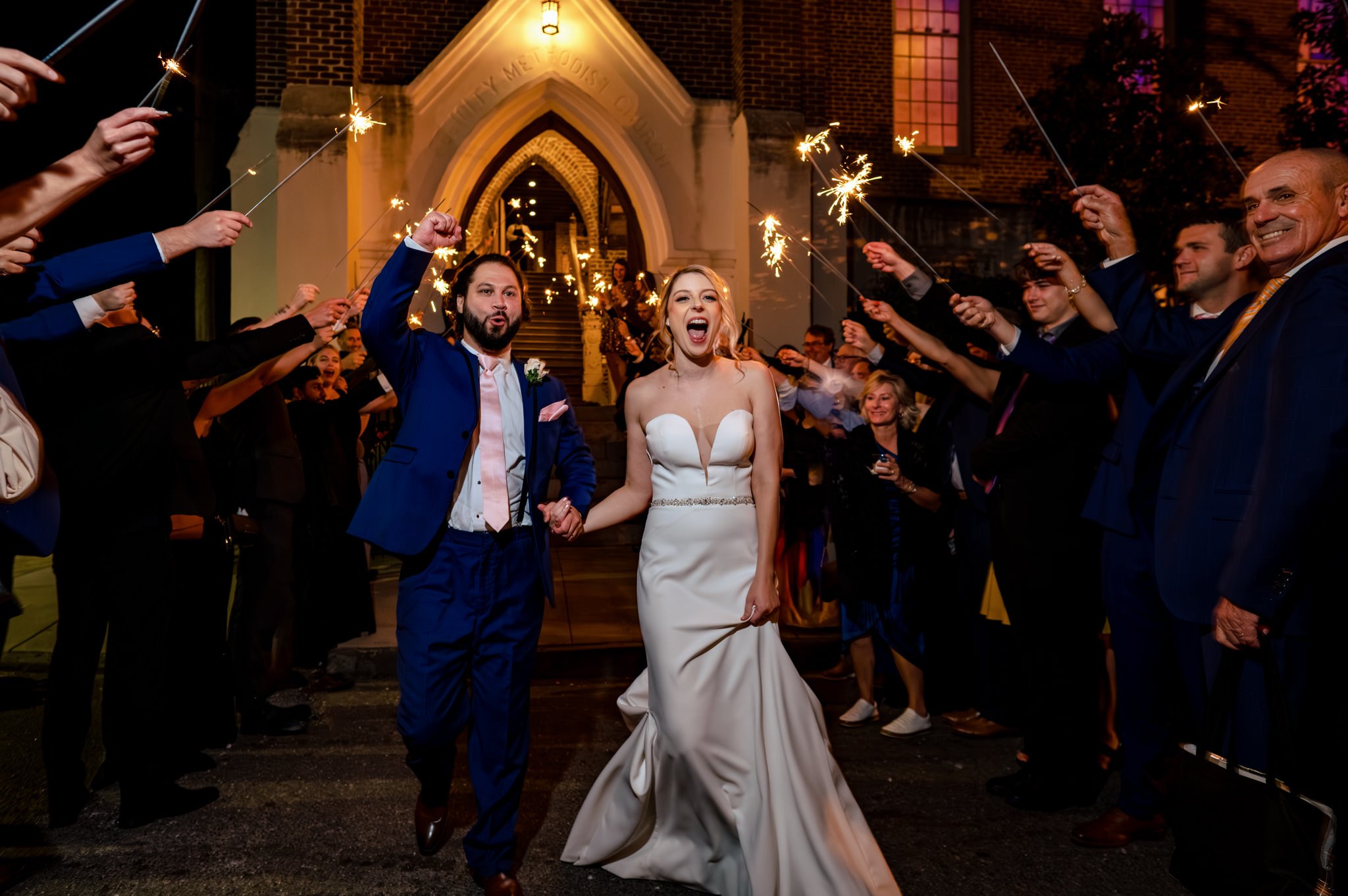 Michael Freas, an exceptional Asheville NC photographer, captures the stunning moments of a bride and groom exiting a church, adorned with sparklers.