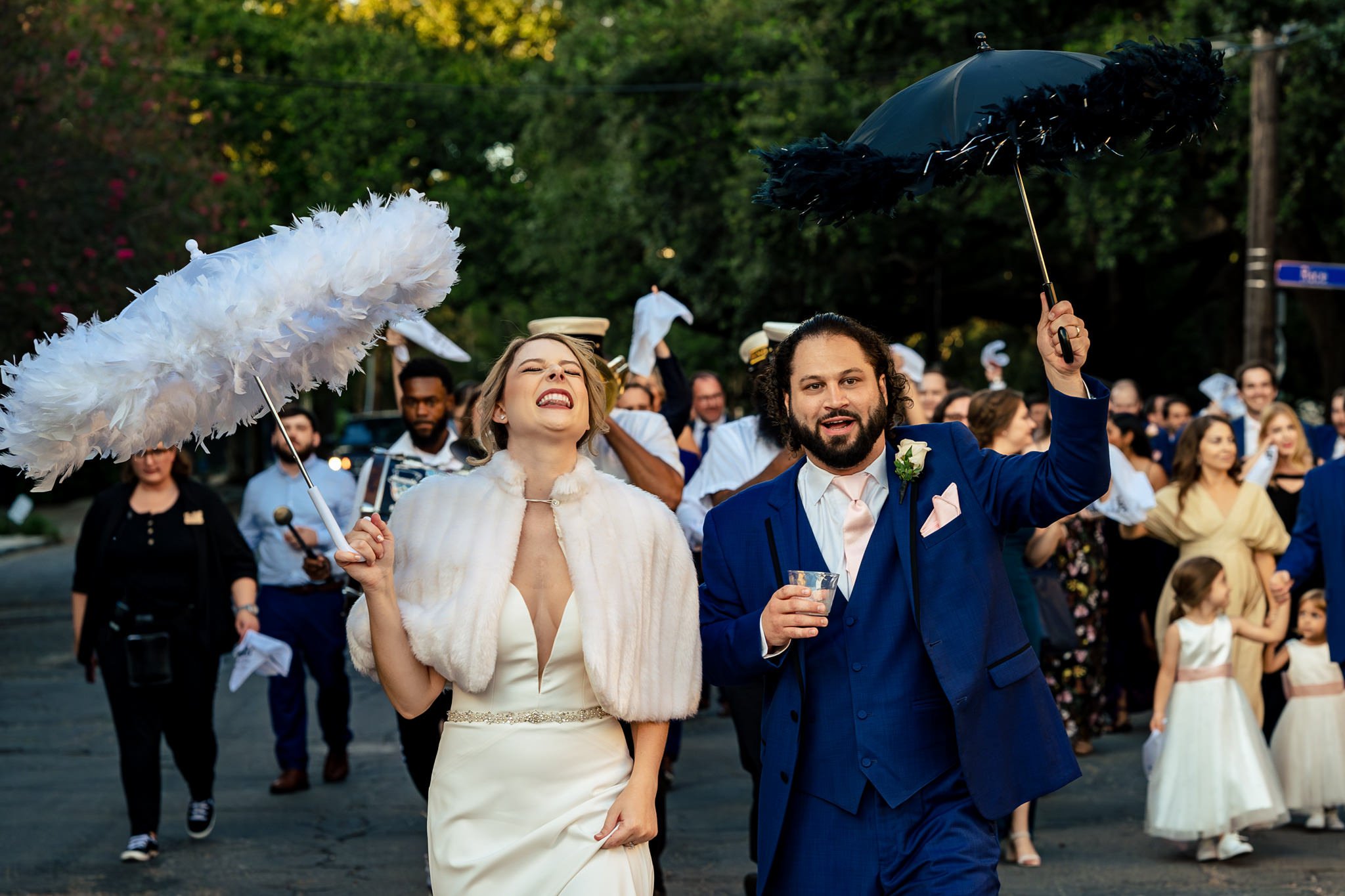 A bride and groom, captured by Asheville, NC photographer Michael Freas, gracefully stroll down the street while holding parasols.