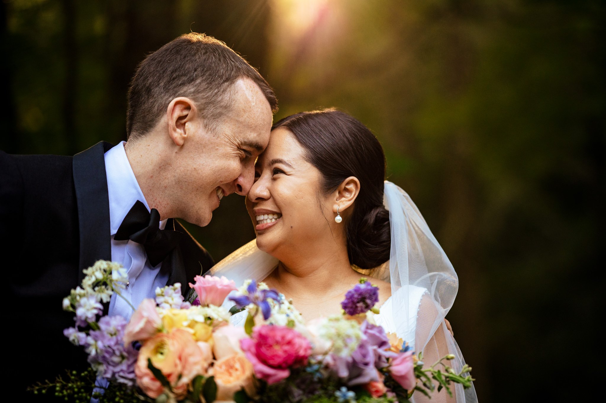 Asheville NC wedding photographer captures a tender kiss between bride and groom in the enchanting woods.