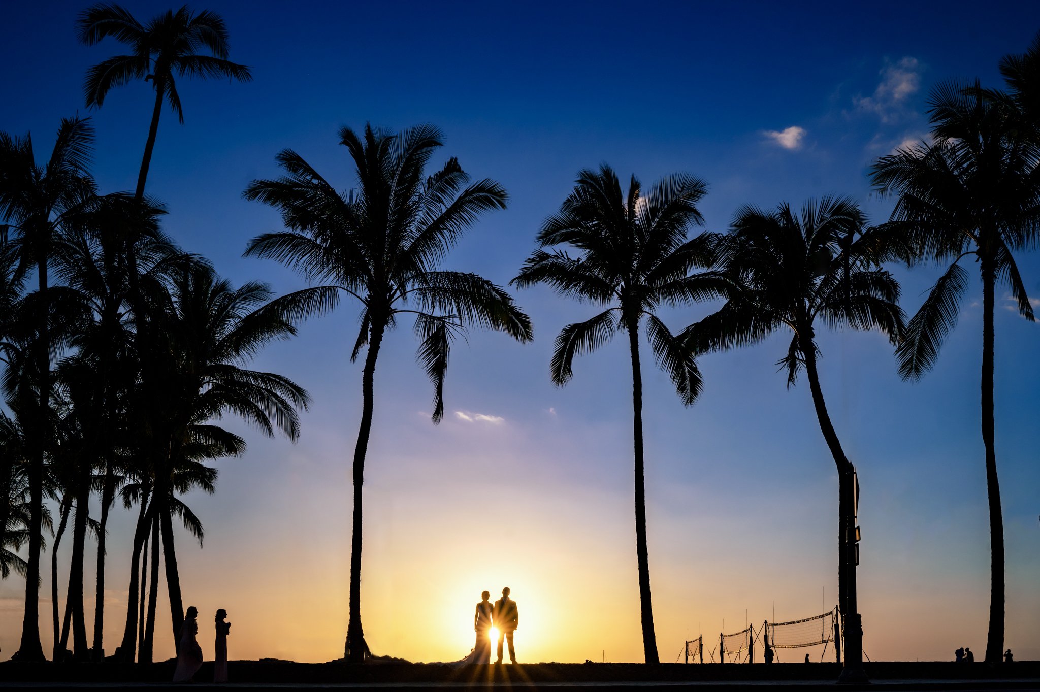 a couple silhouetted in front of palm trees at sunset in honolulu hawaii