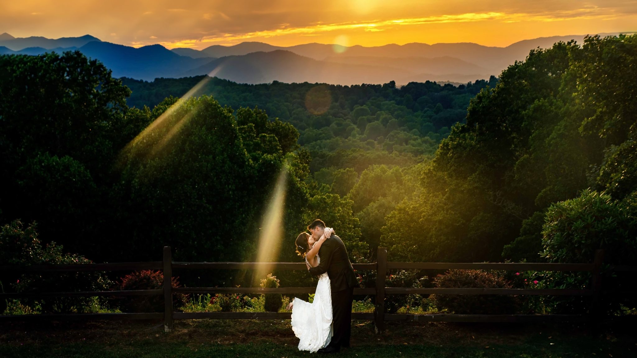Asheville Wedding Photographer captures a bride and groom's kiss in front of beautiful mountains at sunset.