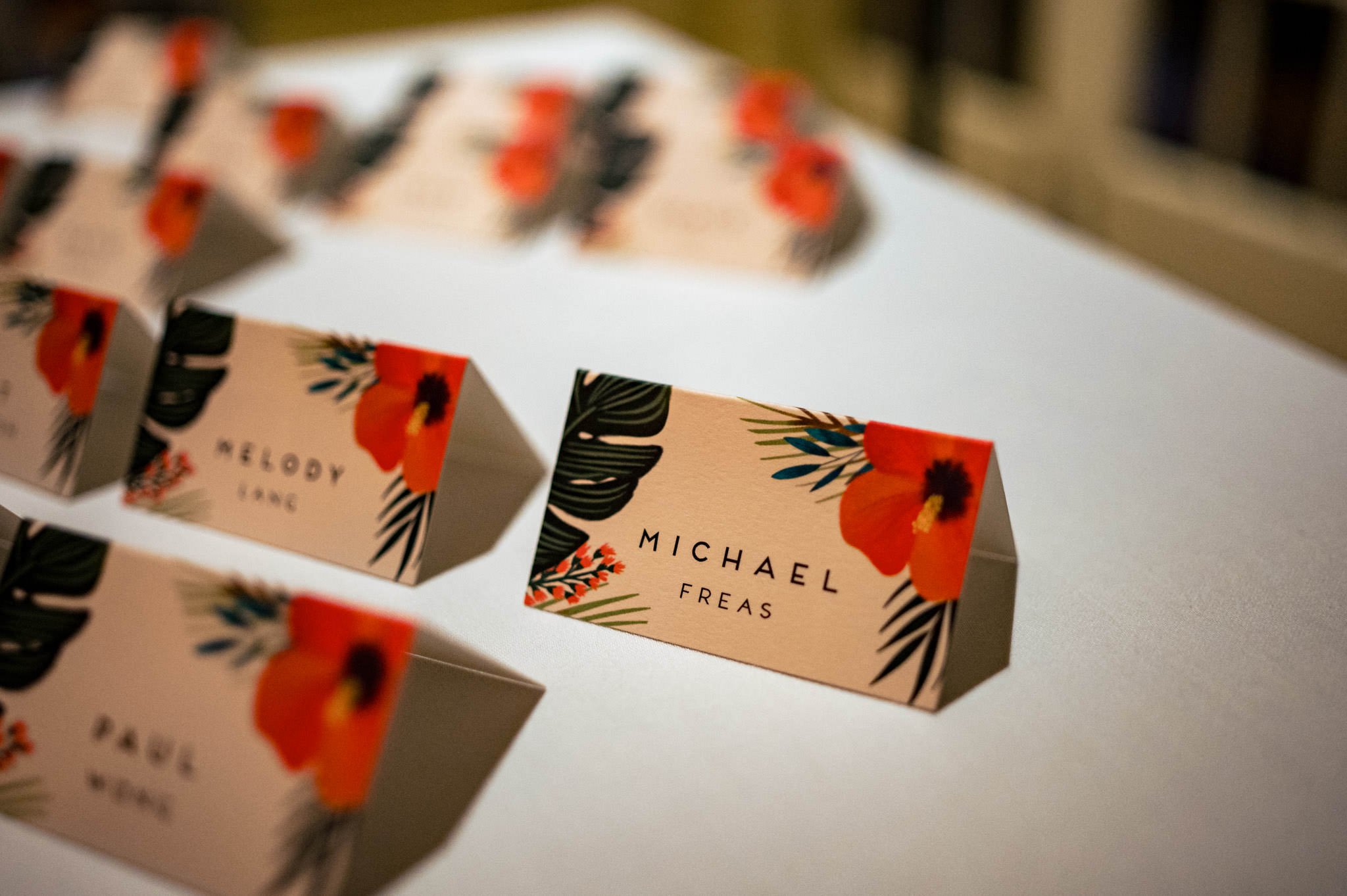 Row of folded place cards with floral design and names; forefront card reads "michael freas" in a destination wedding setting in Honolulu, Hawaii.